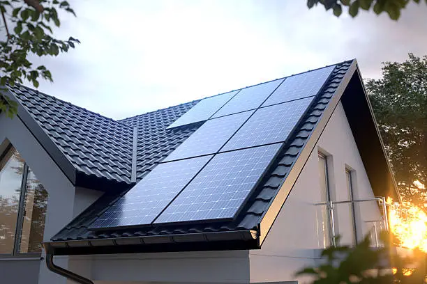 Black solar panels set flush into the tiled roof of a modern house at dusk