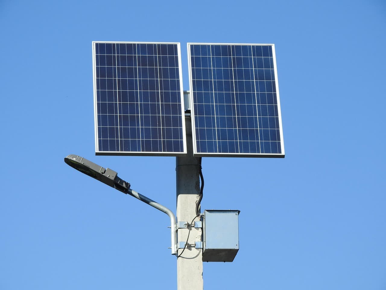 A solar street light with twin panels, a luminaire and a control box on a concrete pole