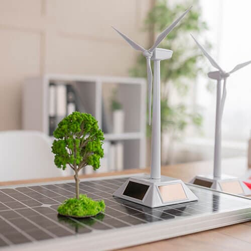 Desktop models of wind turbines and a tree standing on a solar panel